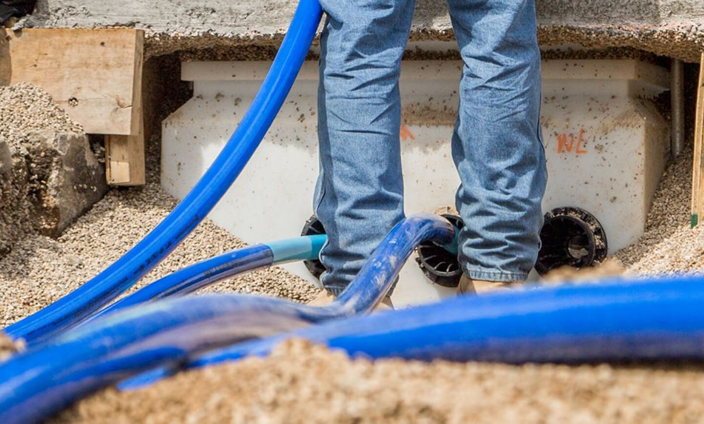 Close up of pipes and tubes on the ground near a man's legs